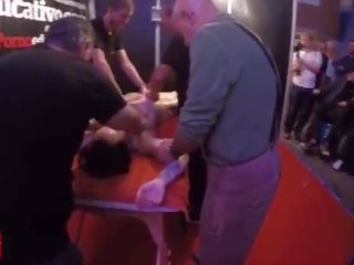 A group of people massage this young and tattoed teenager at the same time in public